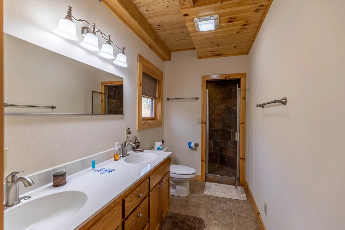 A well-appointed bathroom with double sinks, wooden cabinetry, and a modern shower area. The space is bright, serene, and designed for relaxation and self-care.