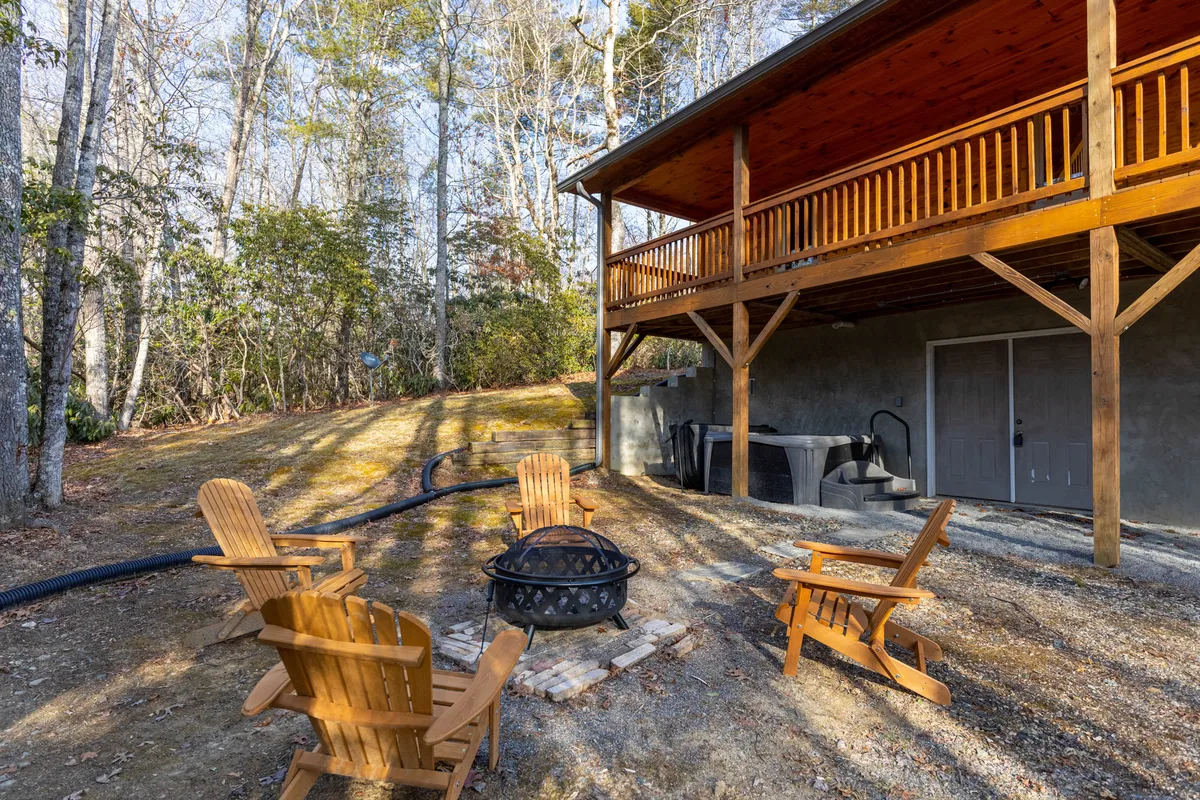 An inviting backyard scene featuring a fire pit surrounded by Adirondack chairs and a wooden deck, ready for evening gatherings under the stars. The setup signals opportunities for socializing, relaxation, and enjoying the mountain air after a day of adventure.